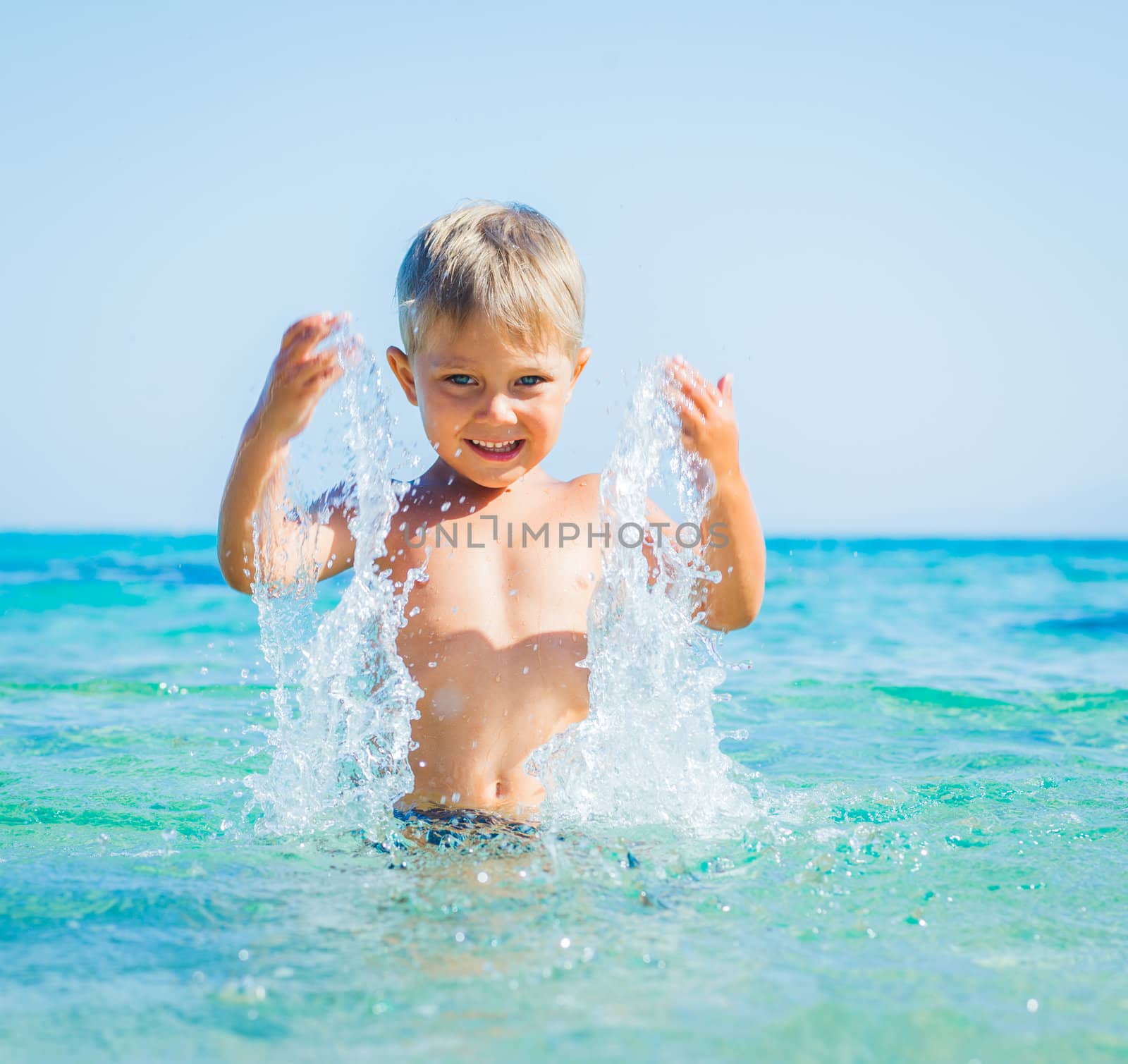 Portrait of young boy swimming and squirting in the transparent sea