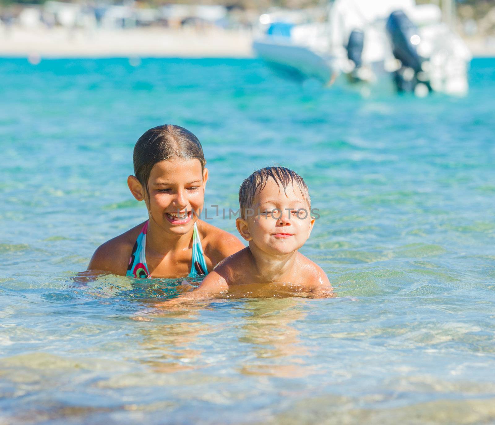 Happy kids. Sister and brother playing and swimming in the transparent sea