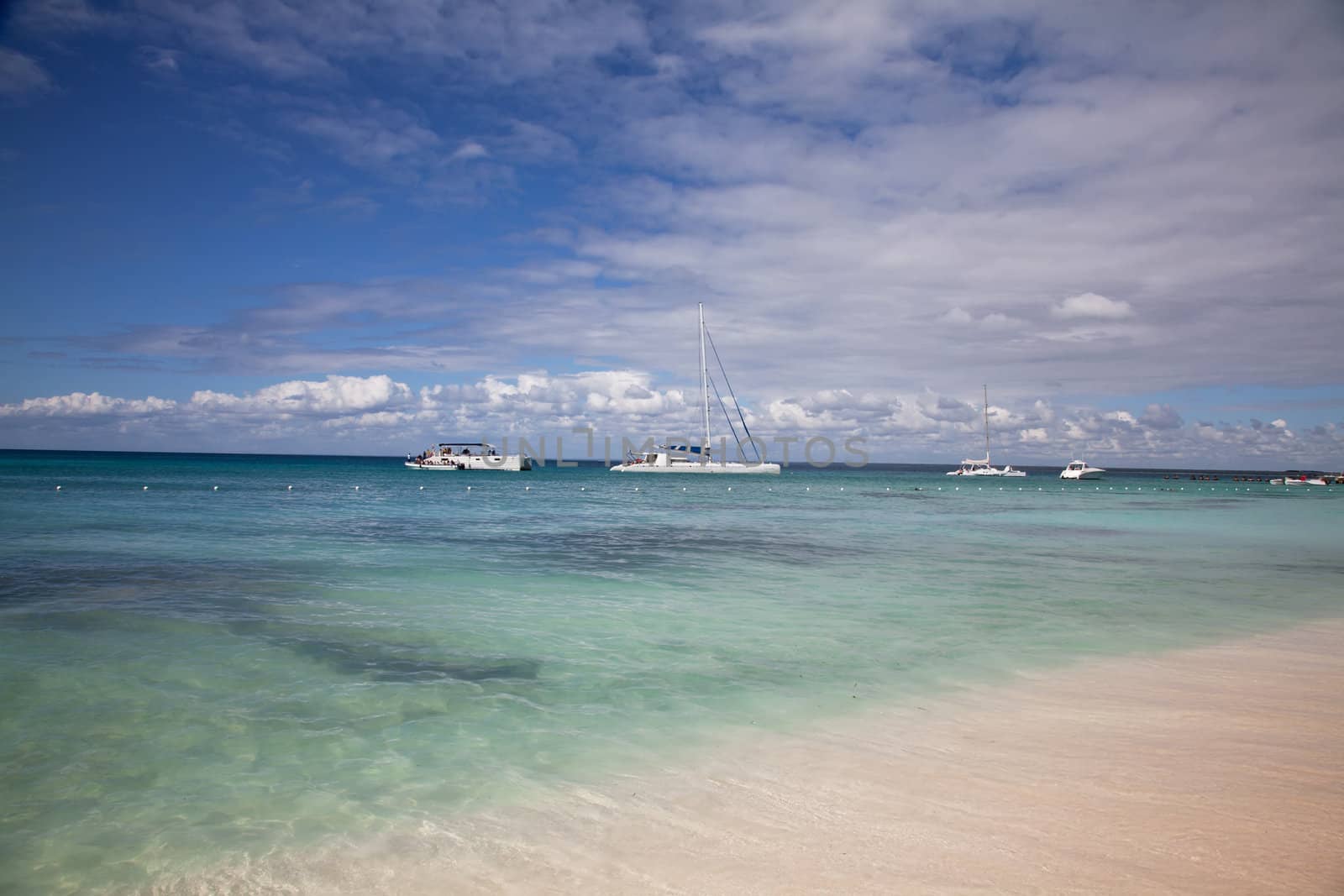 Saona island beach shore with white sand and yacht on the horizon