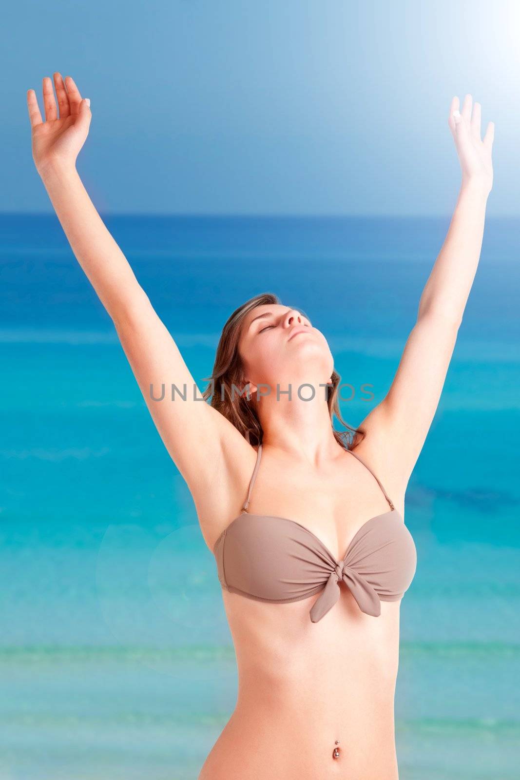 Woman stretching at the beach with the ocean behind