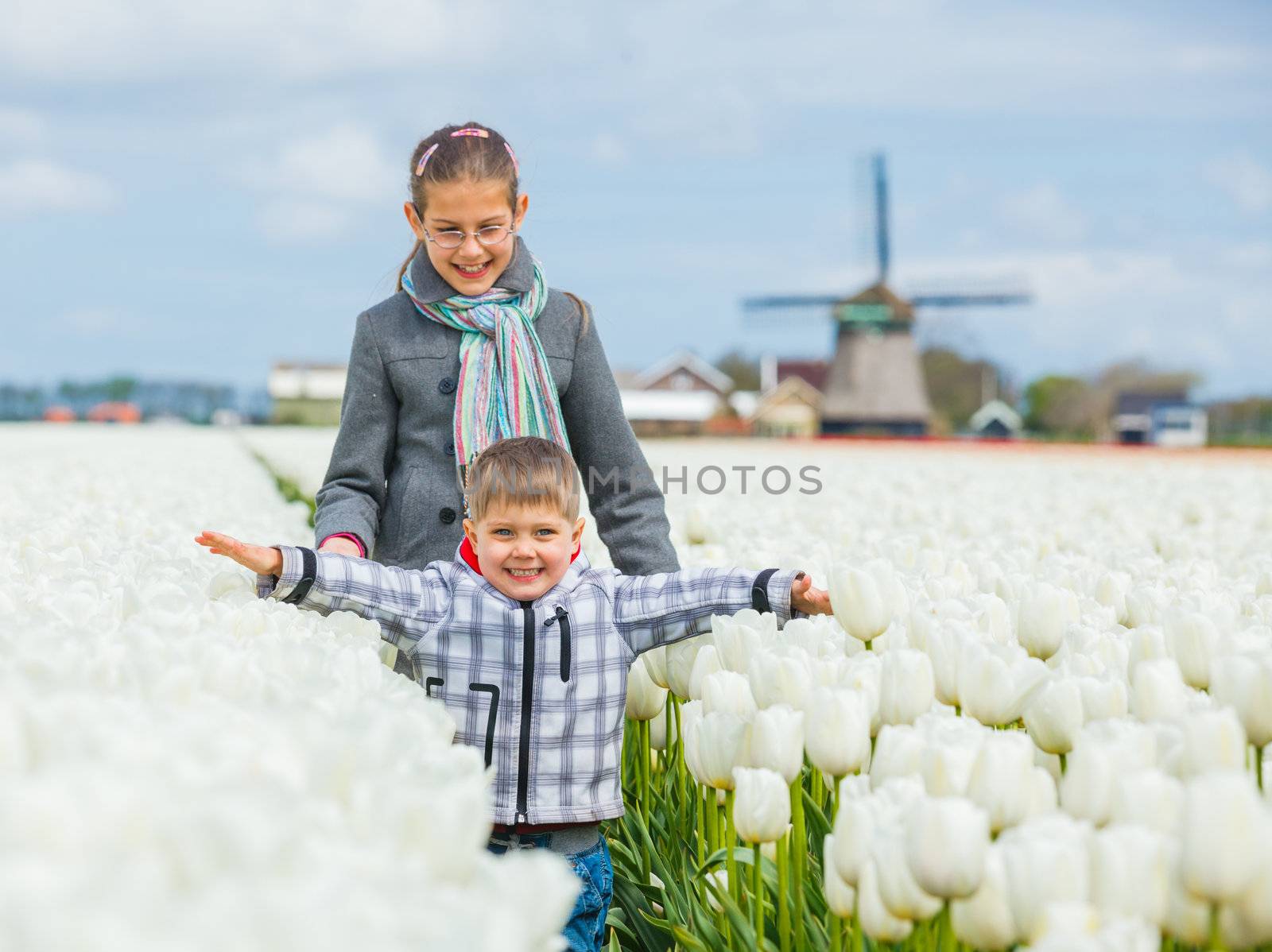 Boy with sister in the tulips field by maxoliki