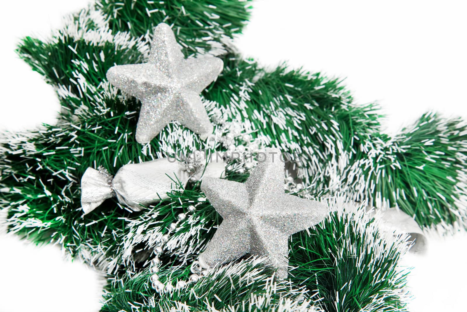 Christmas shiny stars on green tinsel on white background
