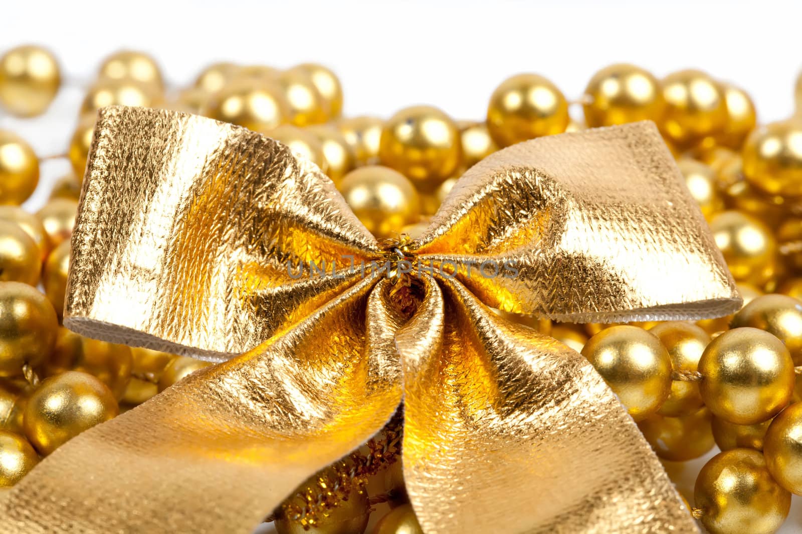 Golden Christmas bow and beads on white background