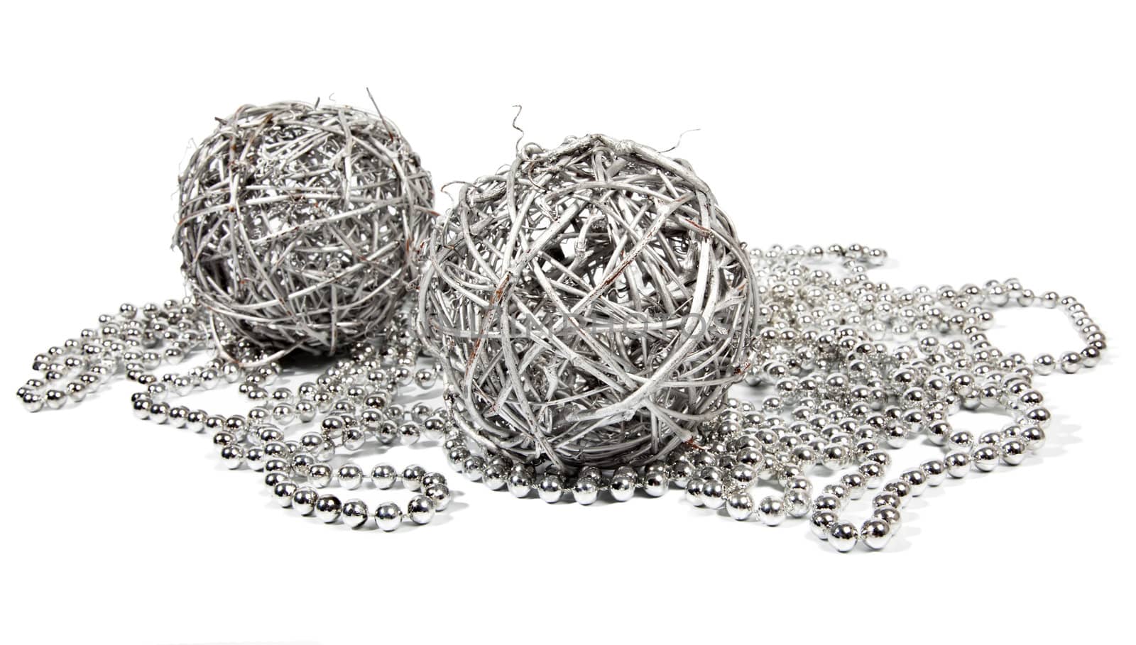 Two wicker balls and silver beads on white background