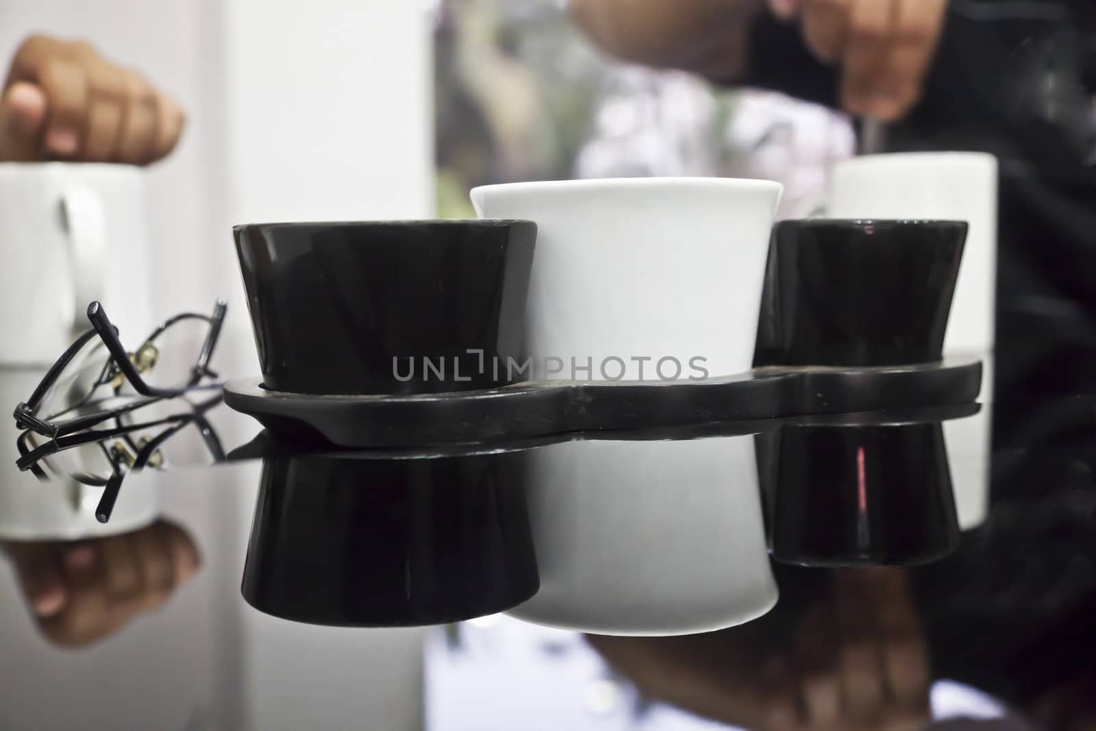 horizontal generic angled abstract in a cafeteria of a asian couple sat having a beverage, black reflective table top, highlights, spectacles coffee mugs and table utensils. Shot location, Goa, India