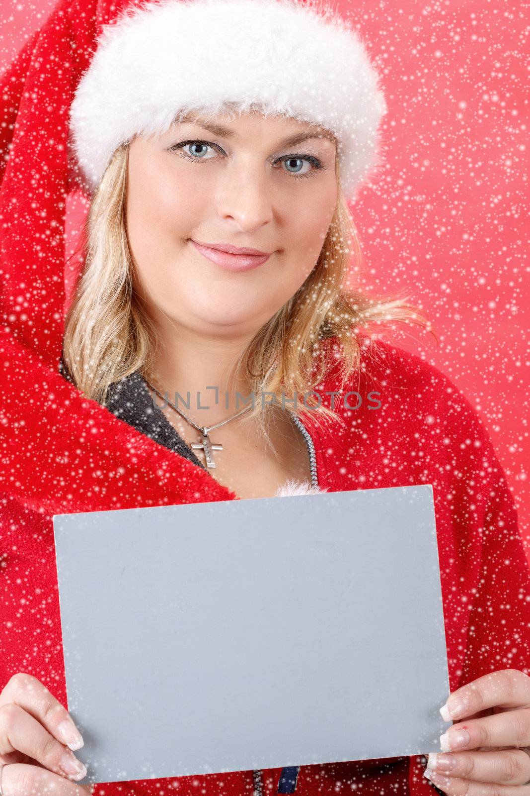 Joyful pretty woman in red santa claus hat smiling on red background