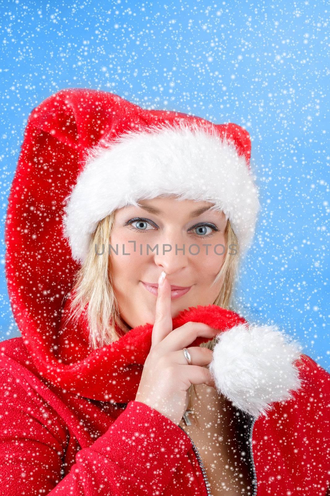 Joyful pretty woman in red santa claus hat smiling on blue background