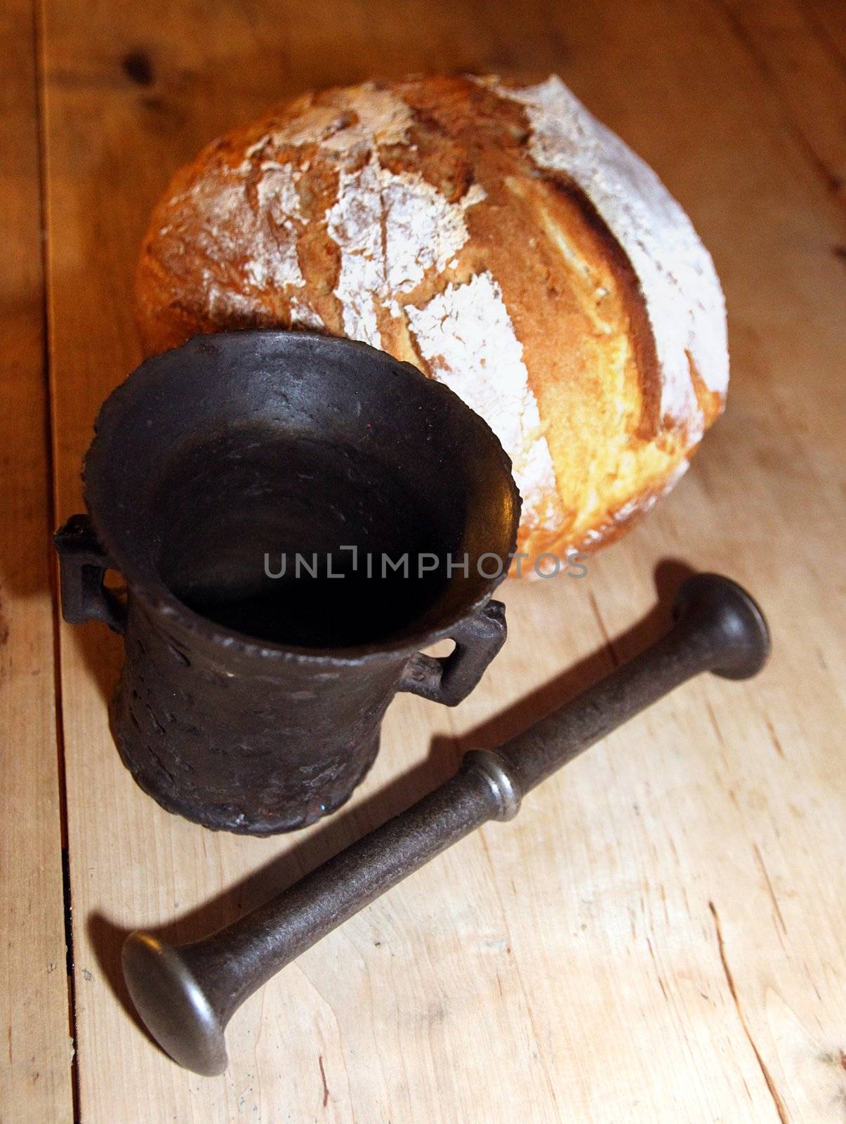 Old iron mortar in front of newly baked peasant bread