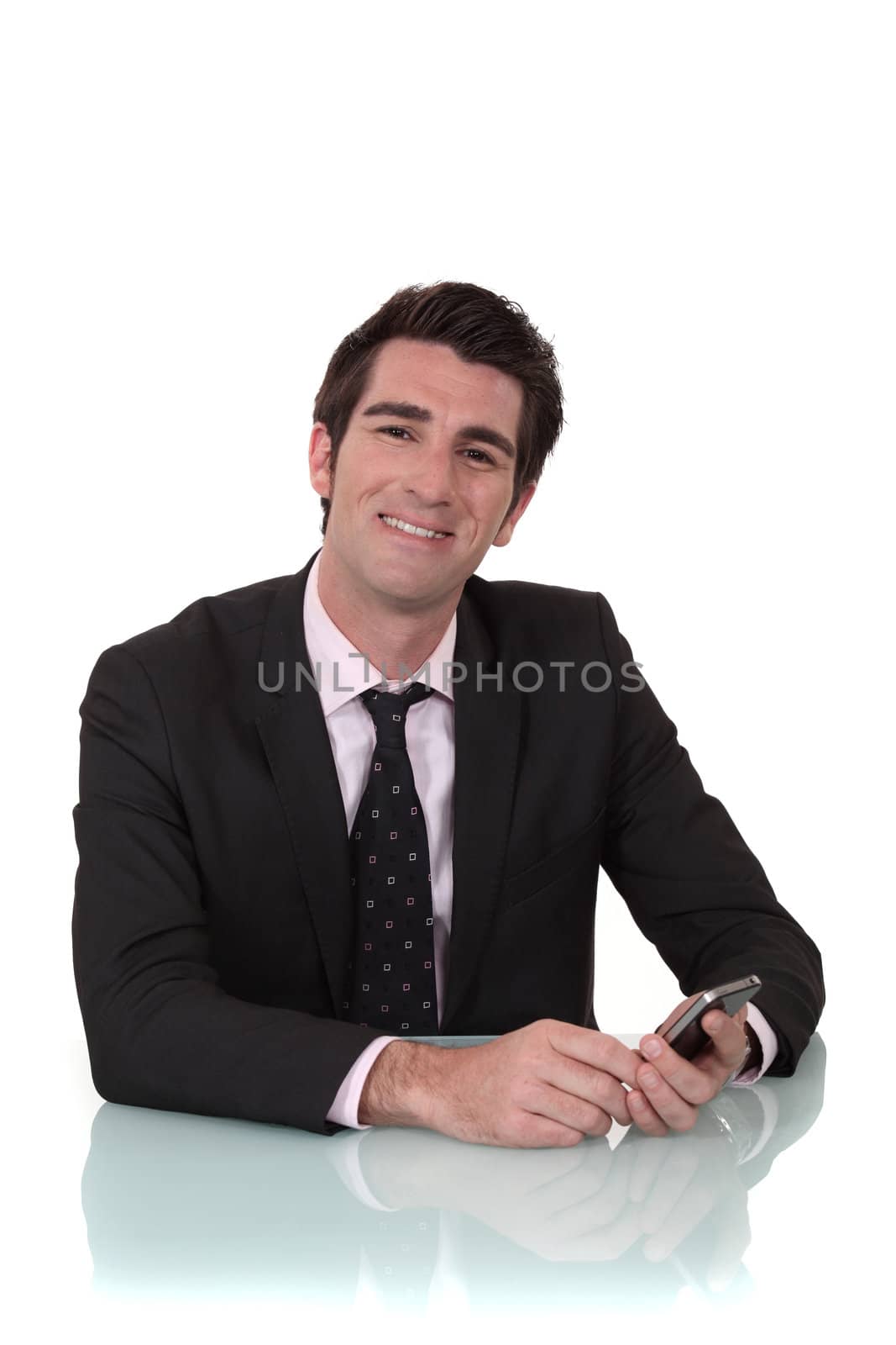 Smiling businessman looking at his mobile phone by phovoir