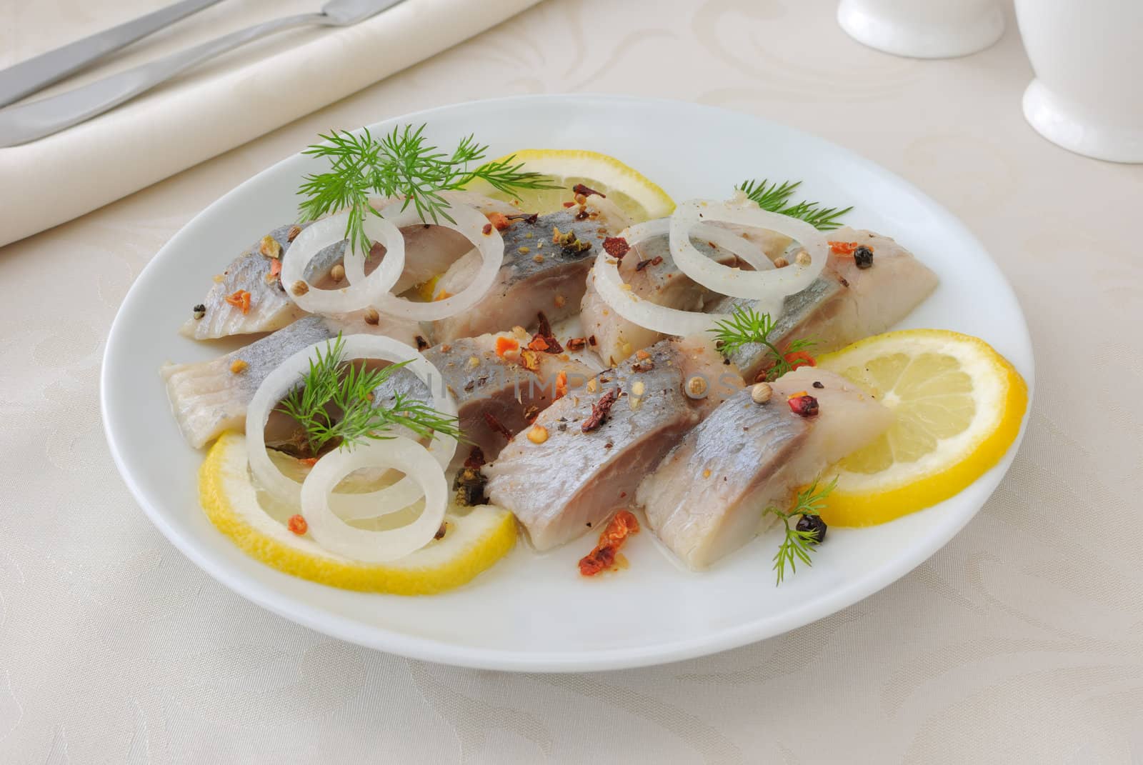 Slices of salted herring fillet with onion, lemon and spices