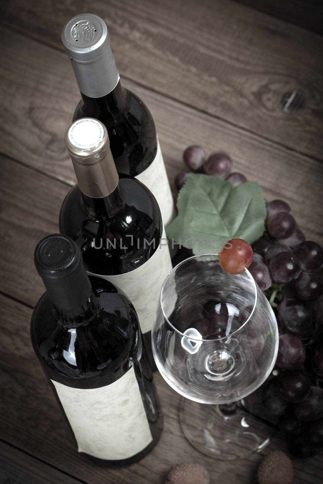 red grapes with wine bottles on brown background by motorolka