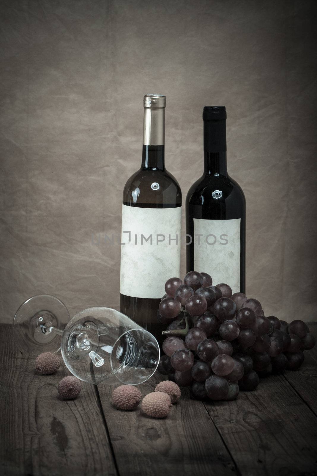 red grapes with wine bottles on brown background