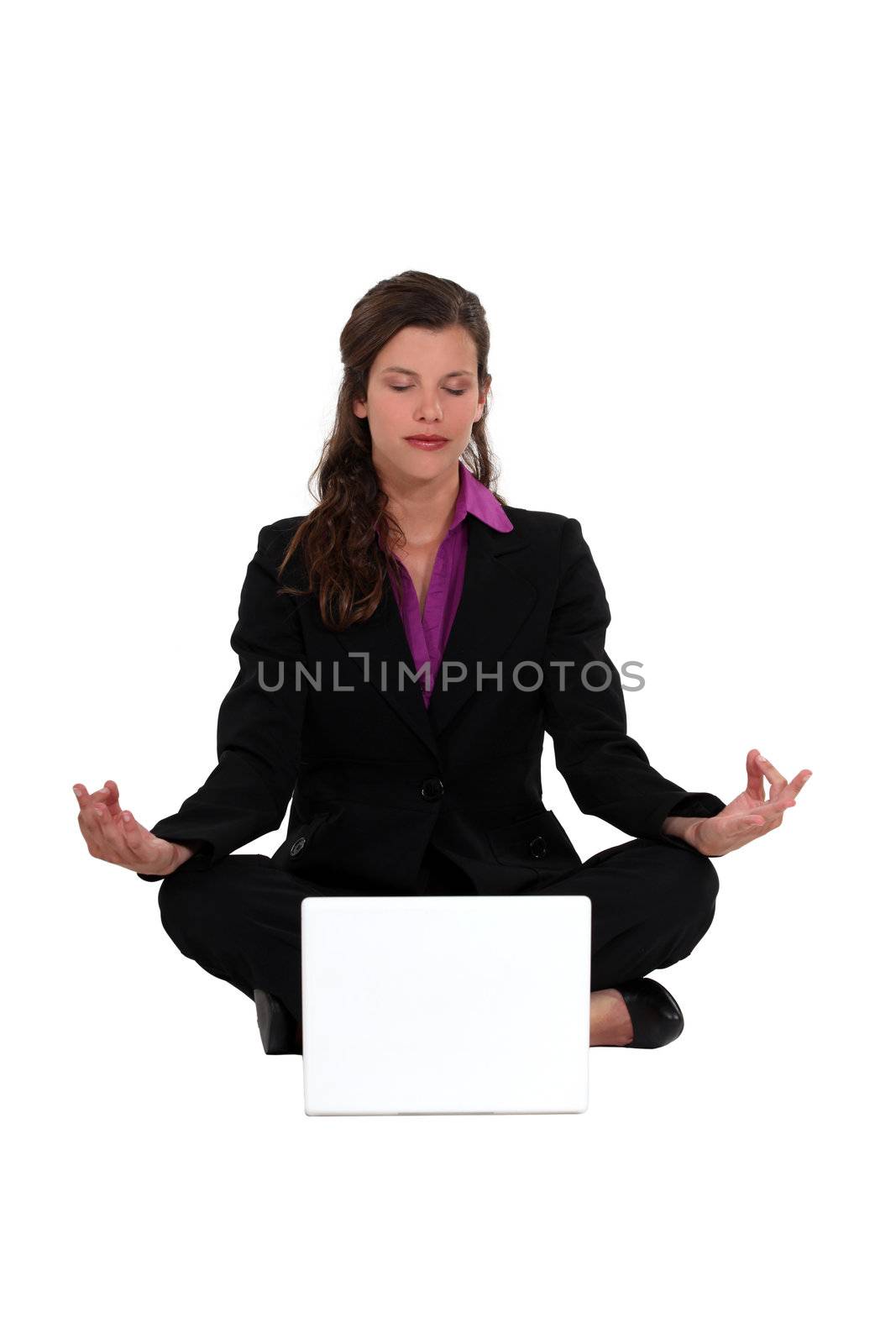 Businesswoman meditating in front of laptop by phovoir