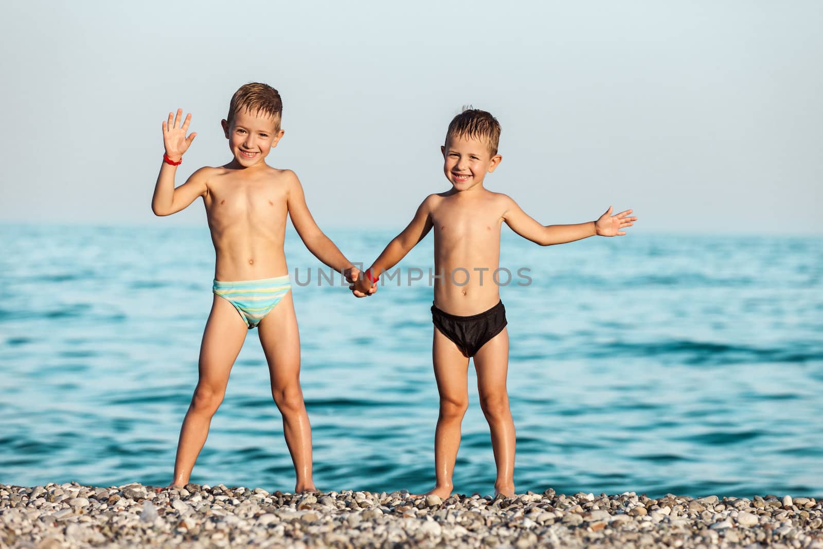Summer vacations - two little child boy brothers playing on blue sea sand beach