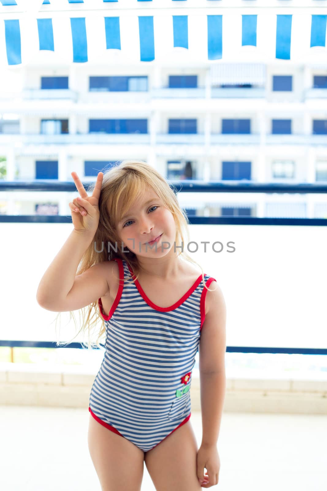 Blond kid girl with summer swimsuit with hands victory sign smiling