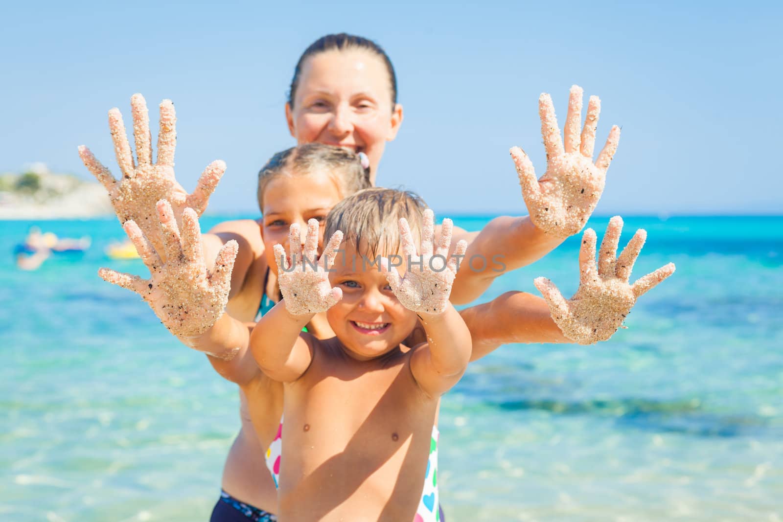 Summer beach - family playing on sandy beach. Focus on the hand