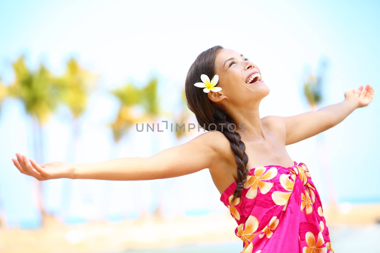 Free happy elated beach woman in freedom joy concept. Beautiful girl smiling with arms out looking up joyful on Hawaiian beach. Mixed race Asian / Caucasian girl.