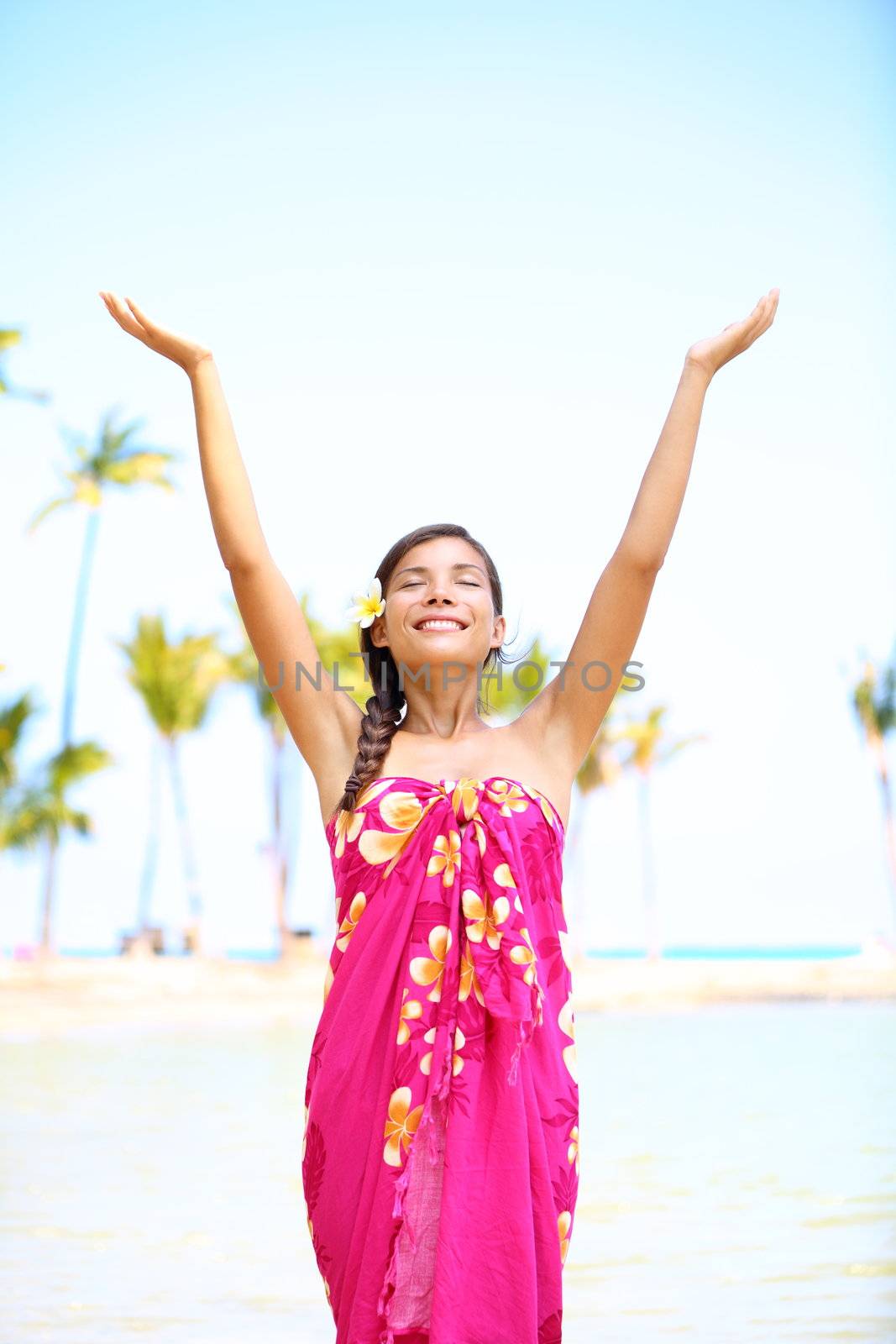 Free spiritual girl on hawaii on beach in meditation freedom pose enjoying Hawaiian beach smiling serene and happy looking up. Multicultural mixed race Asian / Caucasian girl in sarong.