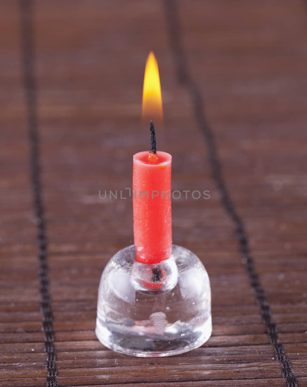 Little red candle over wooden mat background