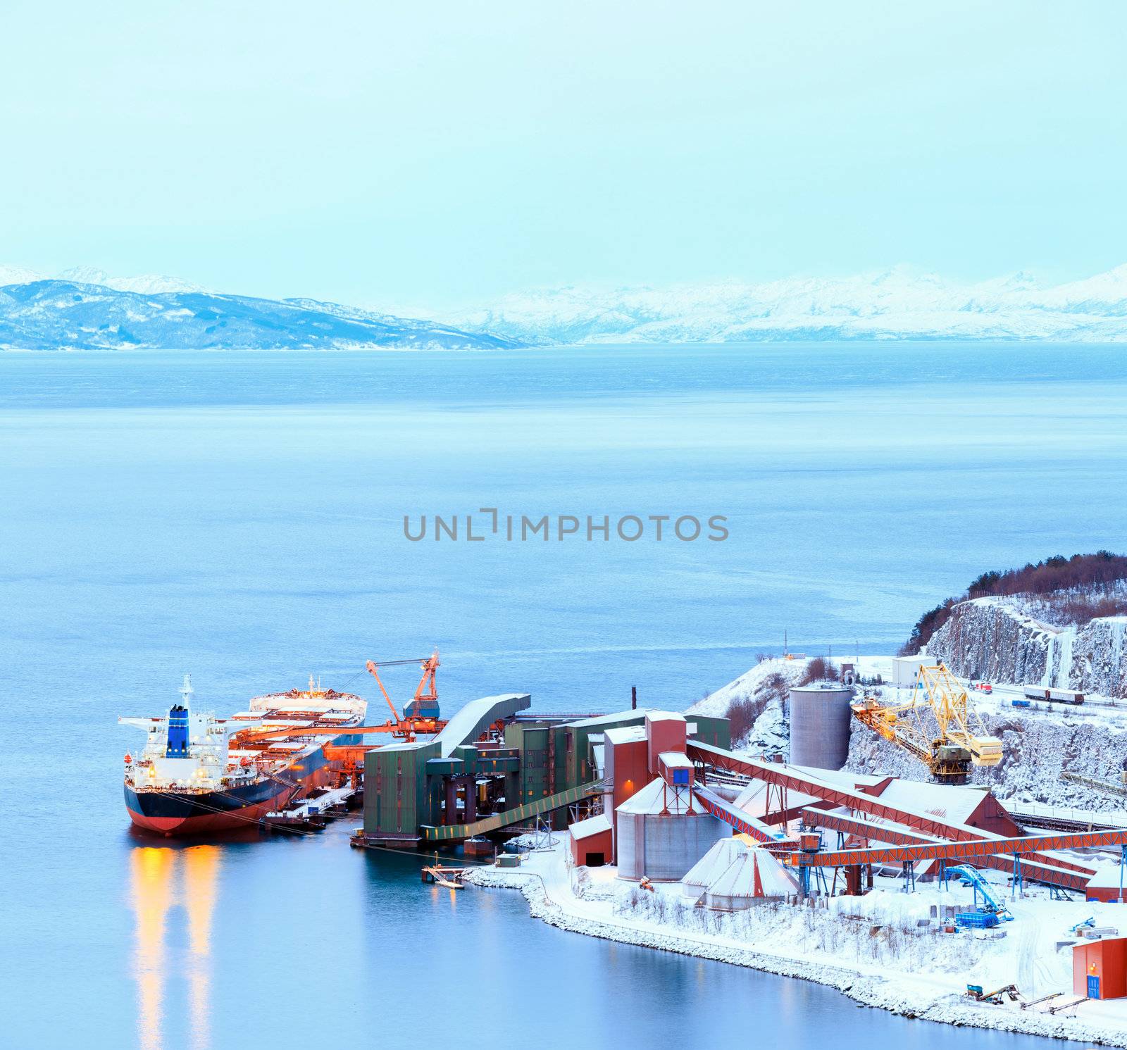 Panorama Industrial Container Cargo freight ship with working crane bridge in shipyard at Iron Ore Mine Factory Plant in Narvik Norway