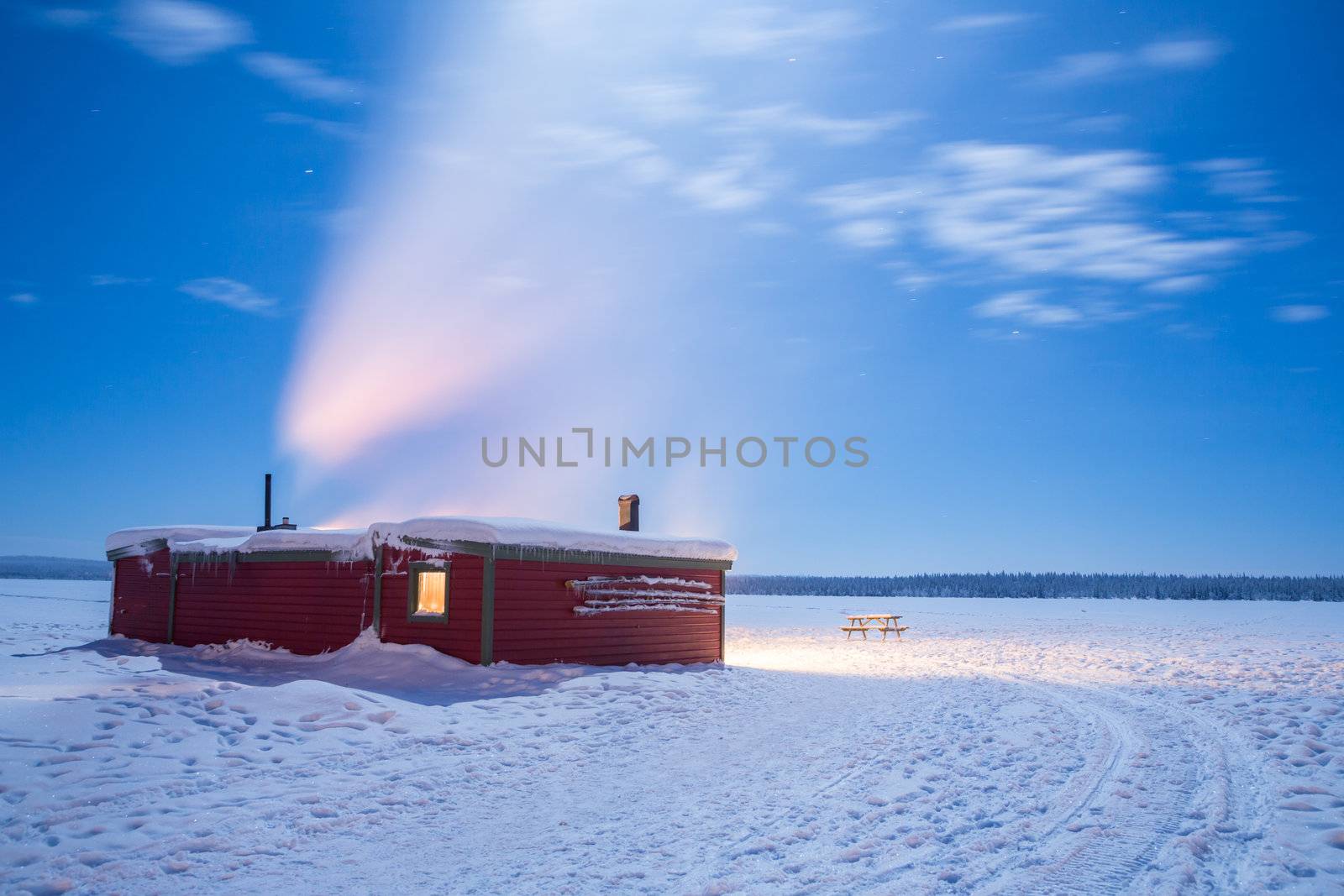 Winter landscape with cabin hut over frozen lake at night in Kiruna Sweden at Night with star trail