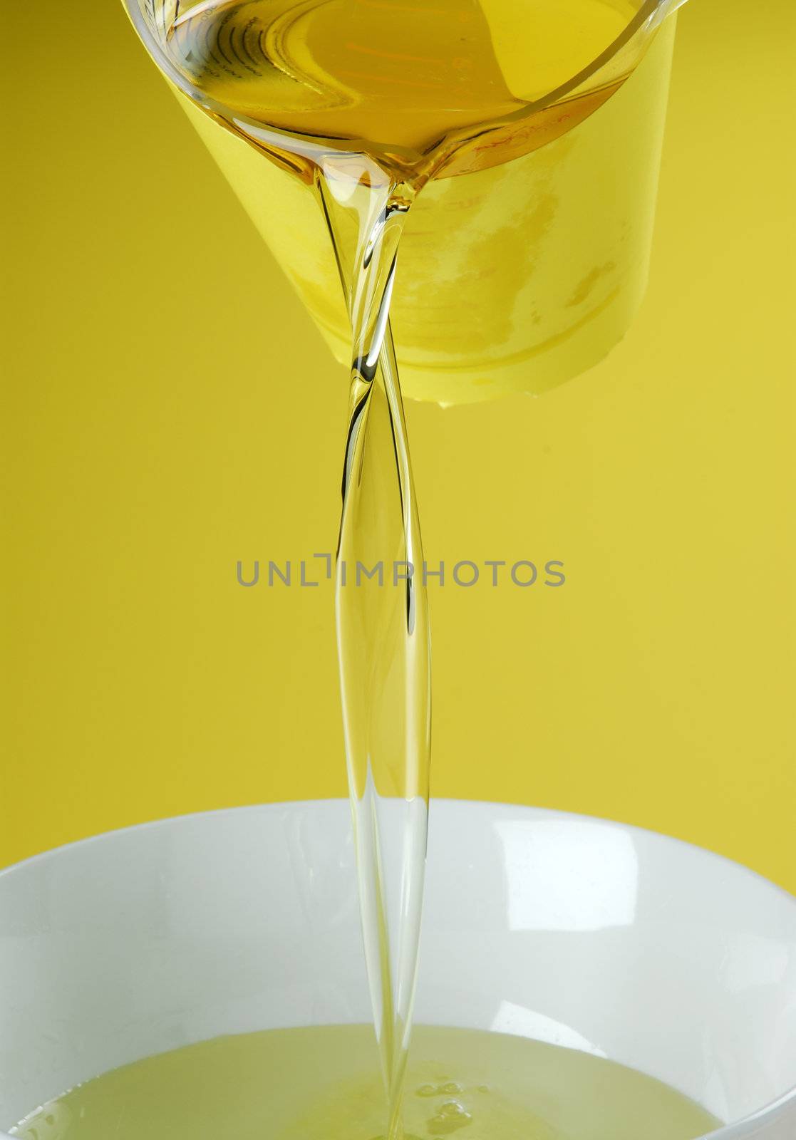 Pouring oil or golden liquid on yellow background