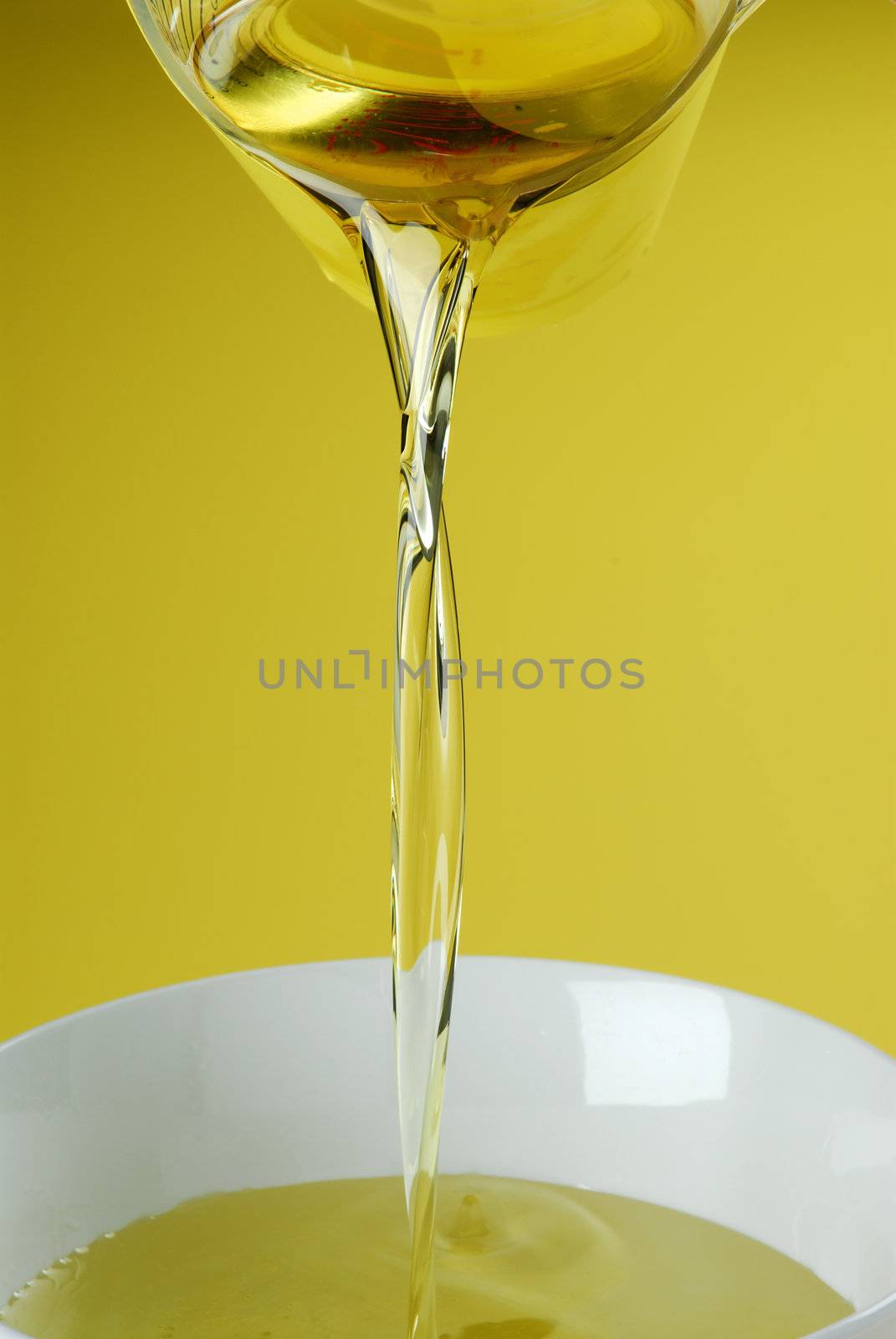 Pouring oil or golden liquid on yellow background