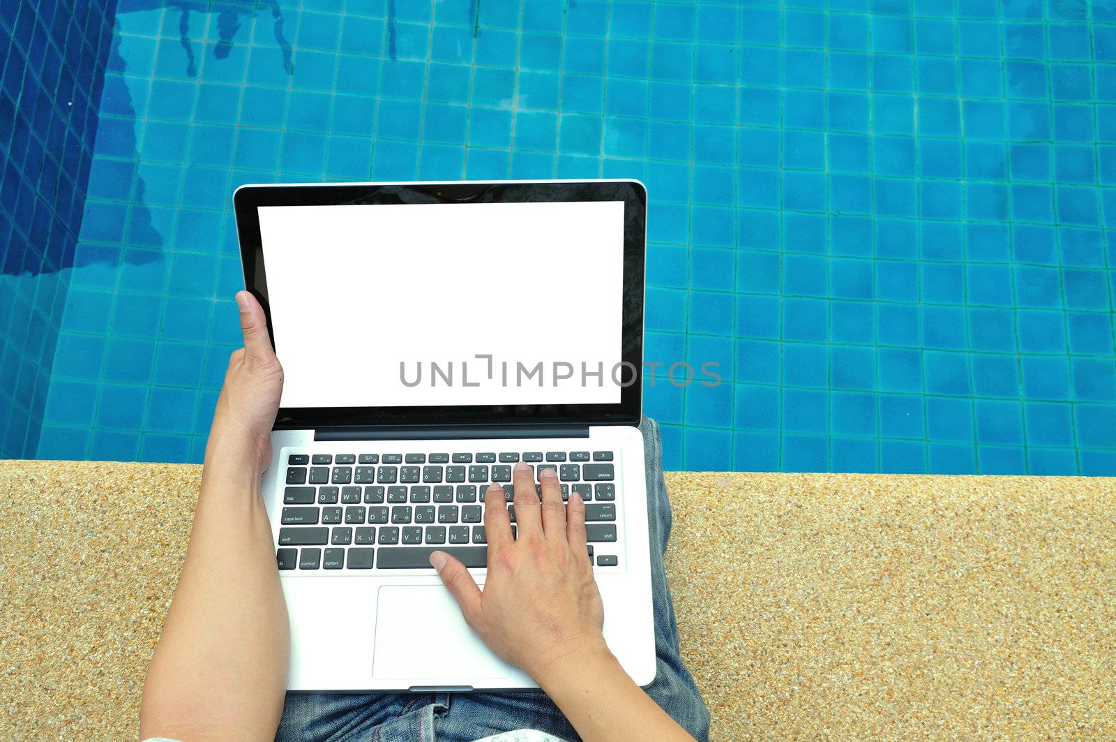 Man using laptop computer beside swimming pool in relax concept