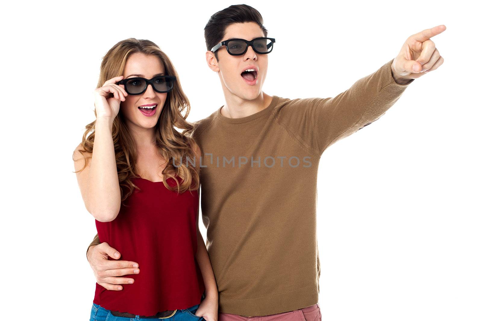 Handsome young man embracing his girl and pointing towards something.