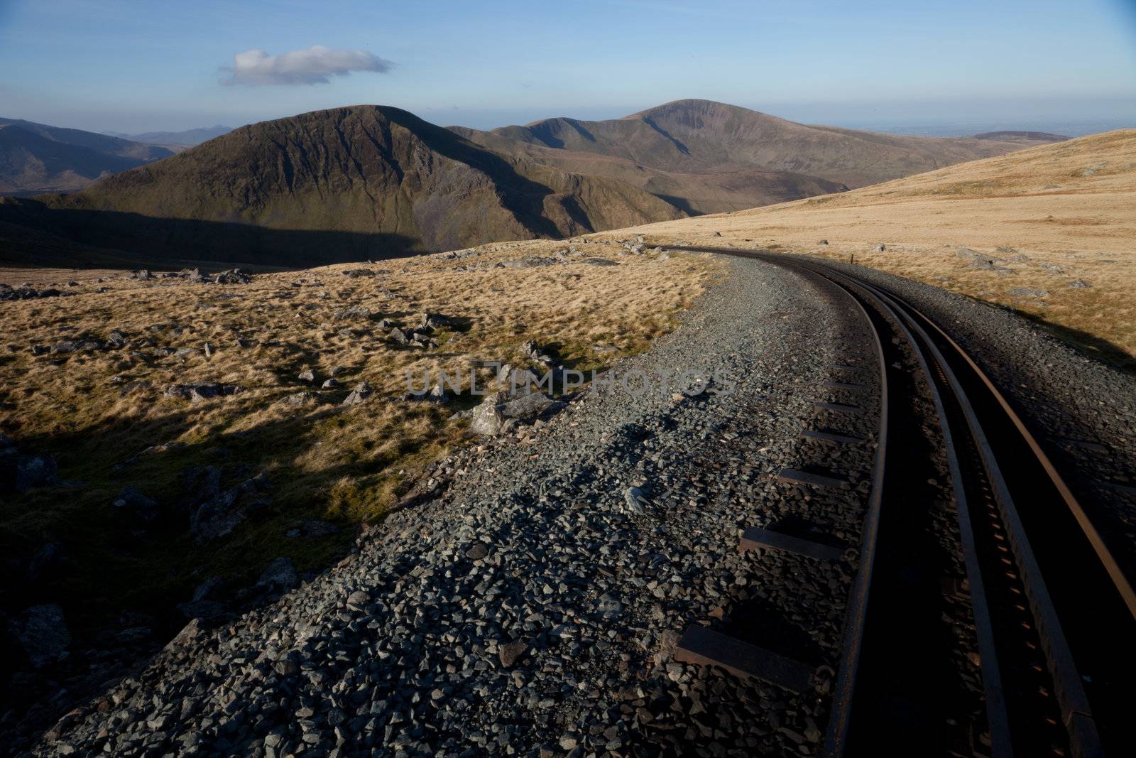 The rack and pinion railway line heading down from Snowdon at dawn with Moel Cynhorion and Elio in the distance.