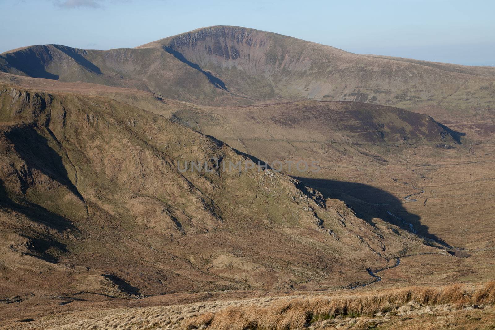 A valley with mountain spurs and river leads to the peak of Moel Eilio, Snowdonia national park, Wales, UK.