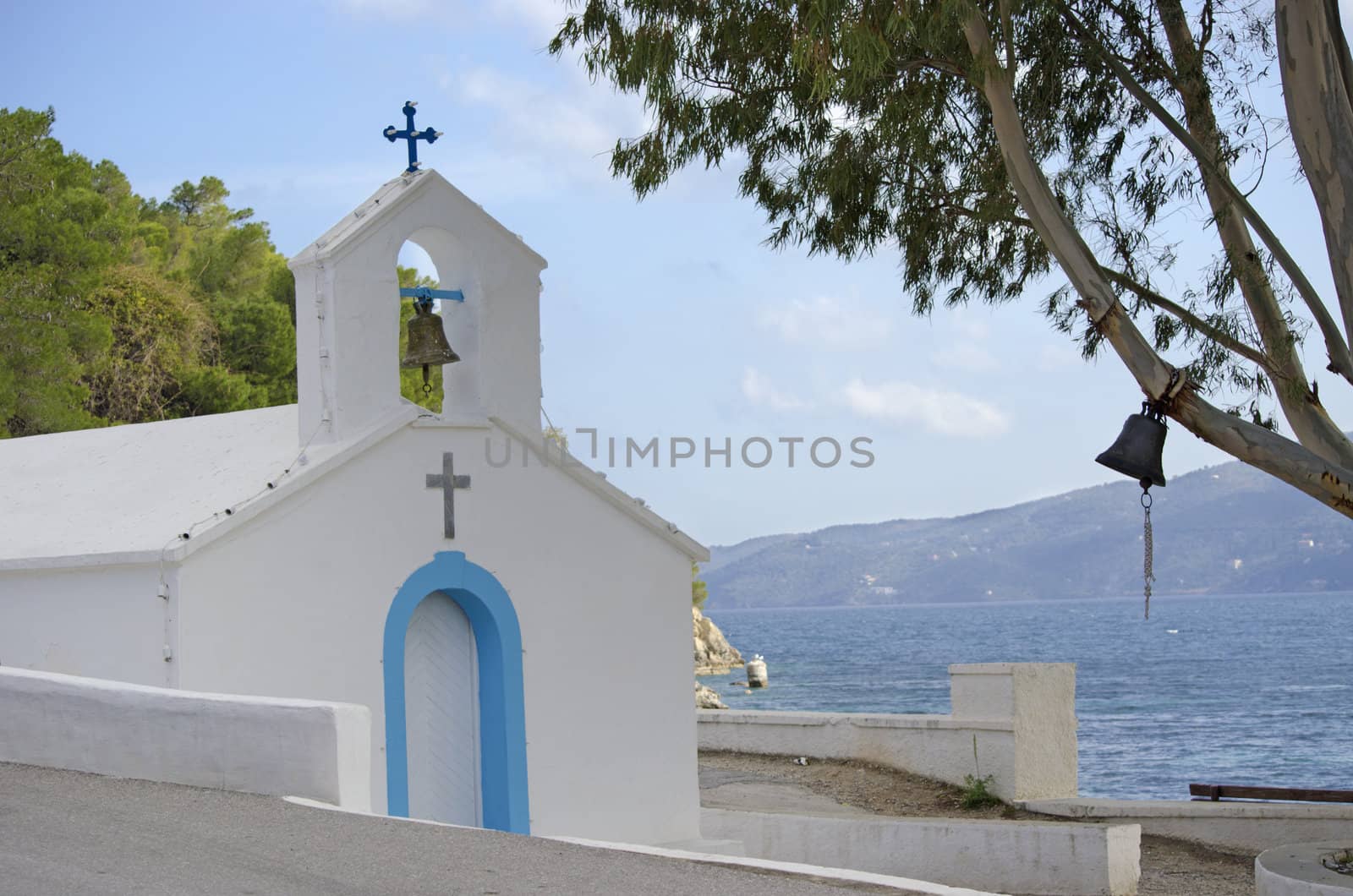 A little white chapel on the island Poros in Greece. The Peleponnese peninsula can be seen in the background.