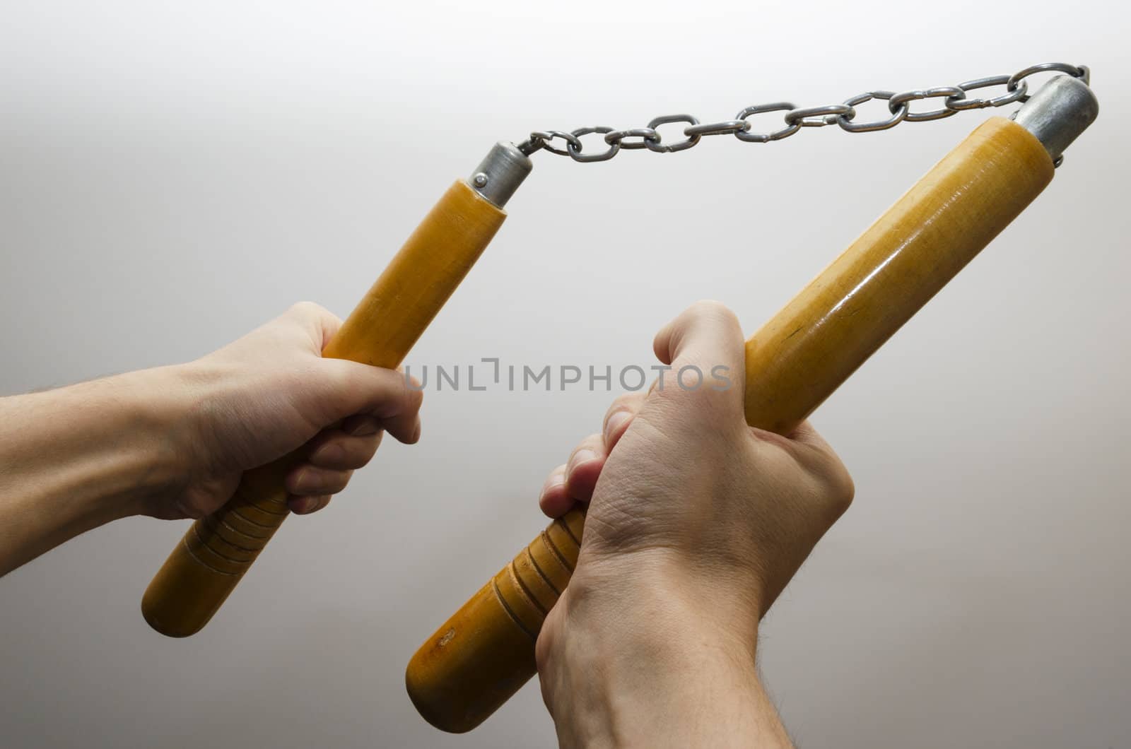 Male hands holding a nunchaku. White backgound.