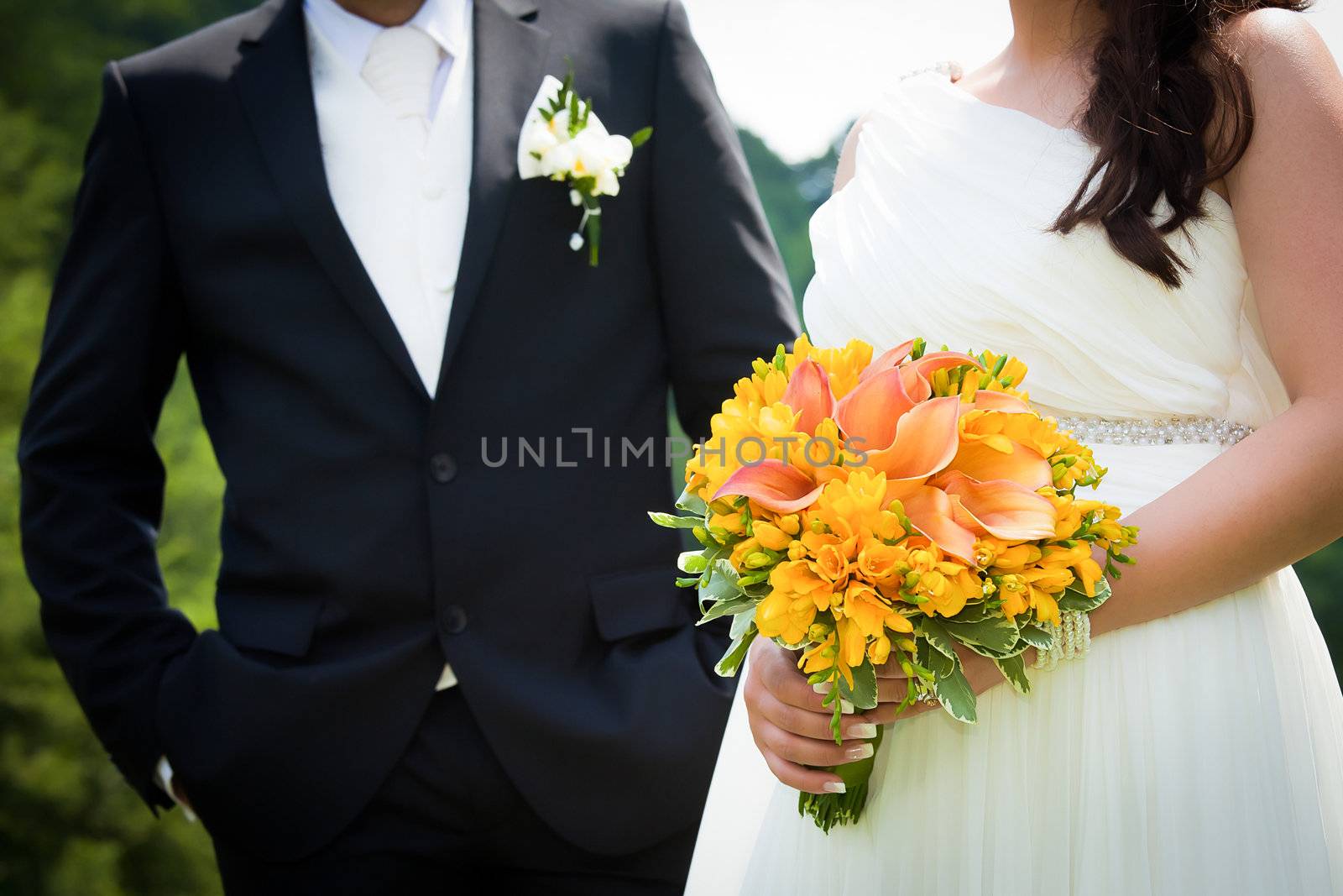 Young married couple holding hands with  wedding bouquet by PixAchi