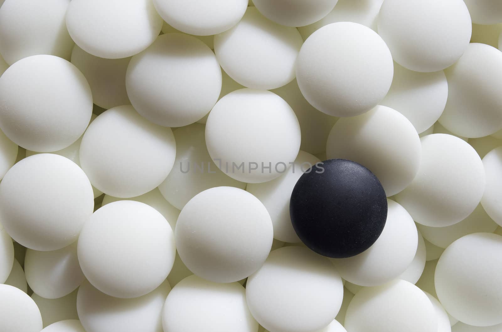 A black go stone lying on a pile of white ones. Go is a traditional Asian strategy game. It is considered to be of the oldest games in the world.