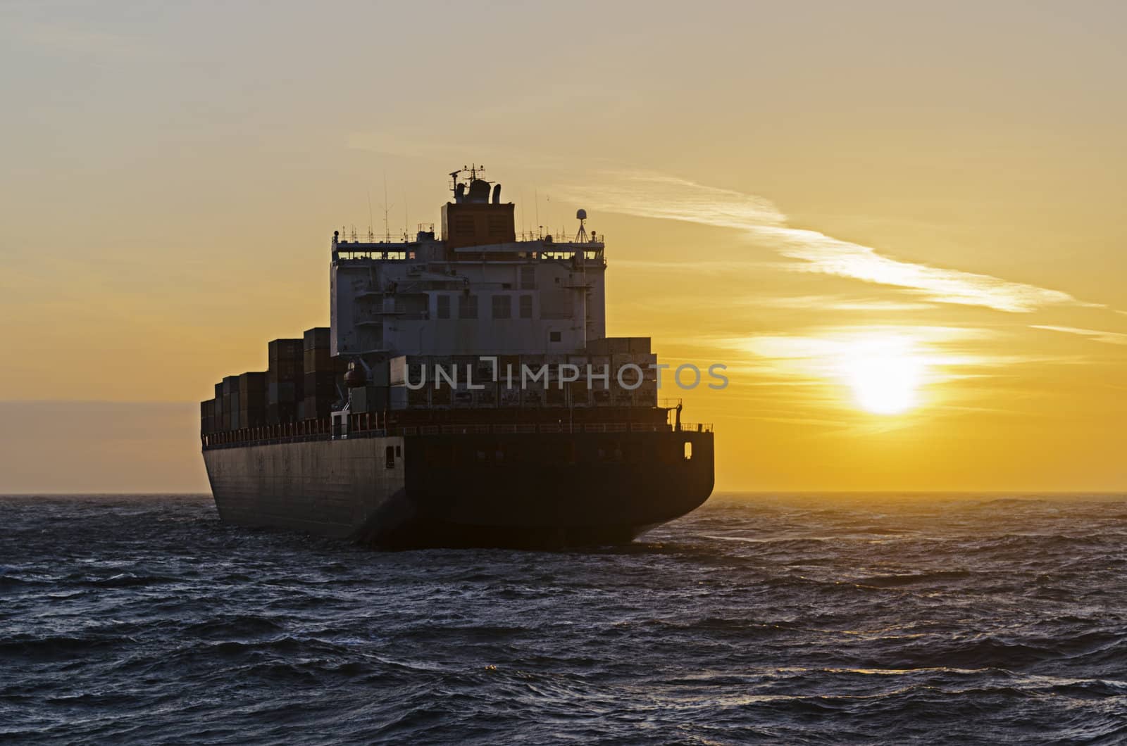 Container ship heading towards sunset on the north sea in Germany.