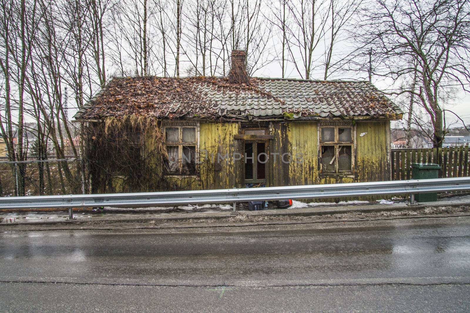 the nature has taken over, it grows weeds, wilderness, shrubs and bushes along the walls and roof of the house, the image is shot in december in a street in Halden called "river street"