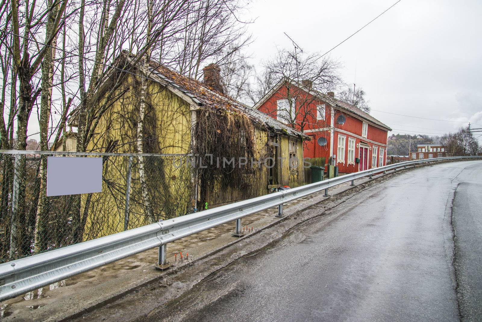 the nature has taken over, it grows weeds, wilderness, shrubs and bushes along the walls and roof of the house, the image is shot in december in a street in Halden called "river street"