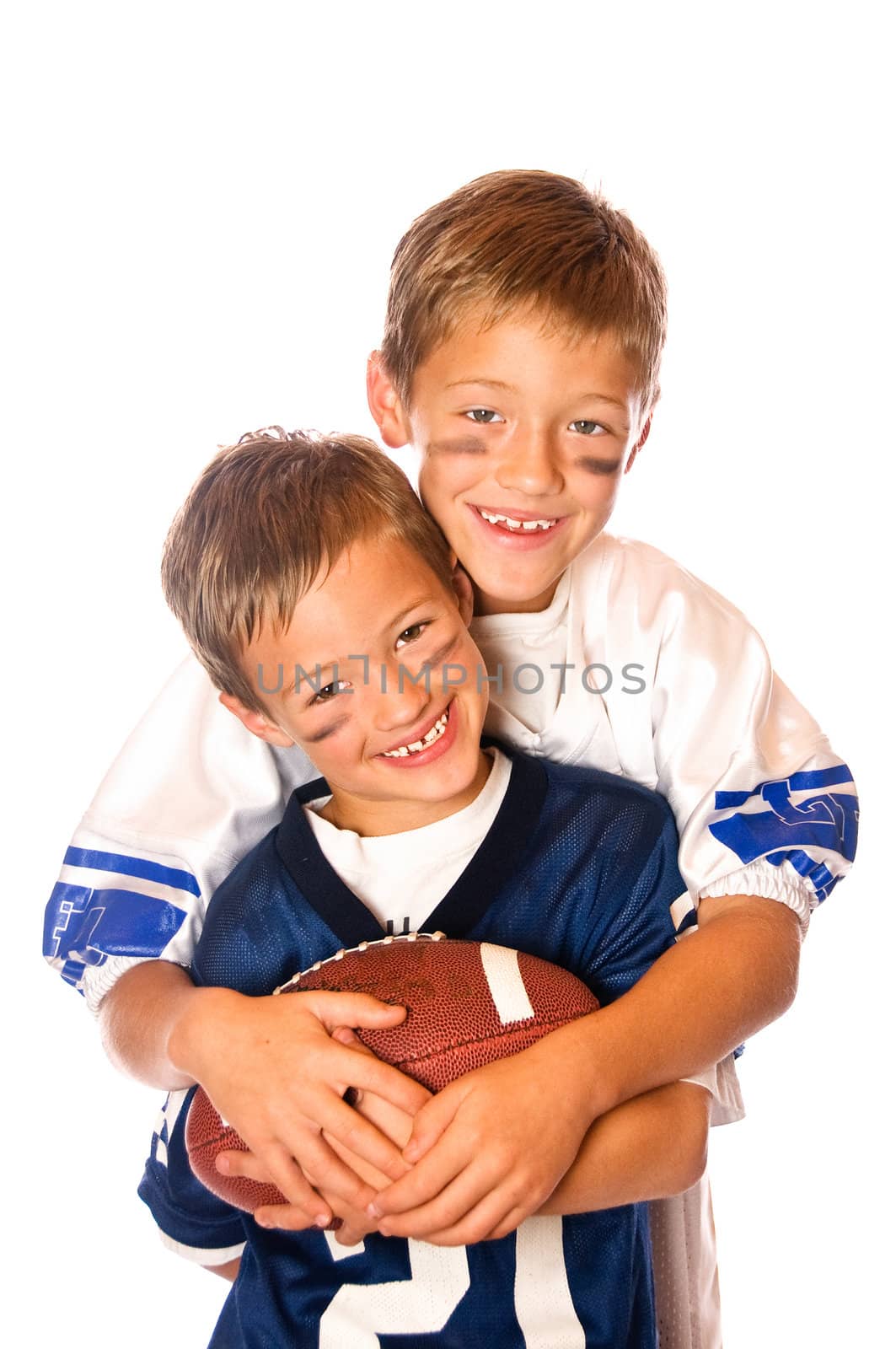 Two cute young boys in jerseys holding a football.  Isolated on white.