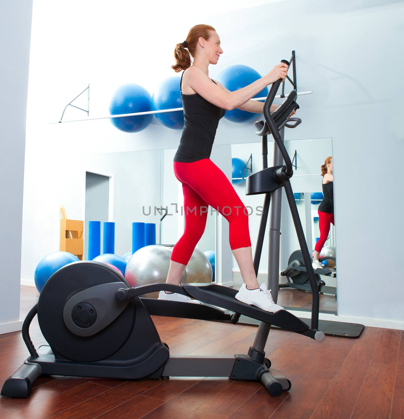 Aerobics cardio training woman on elliptic crosstrainer bicycle at gym