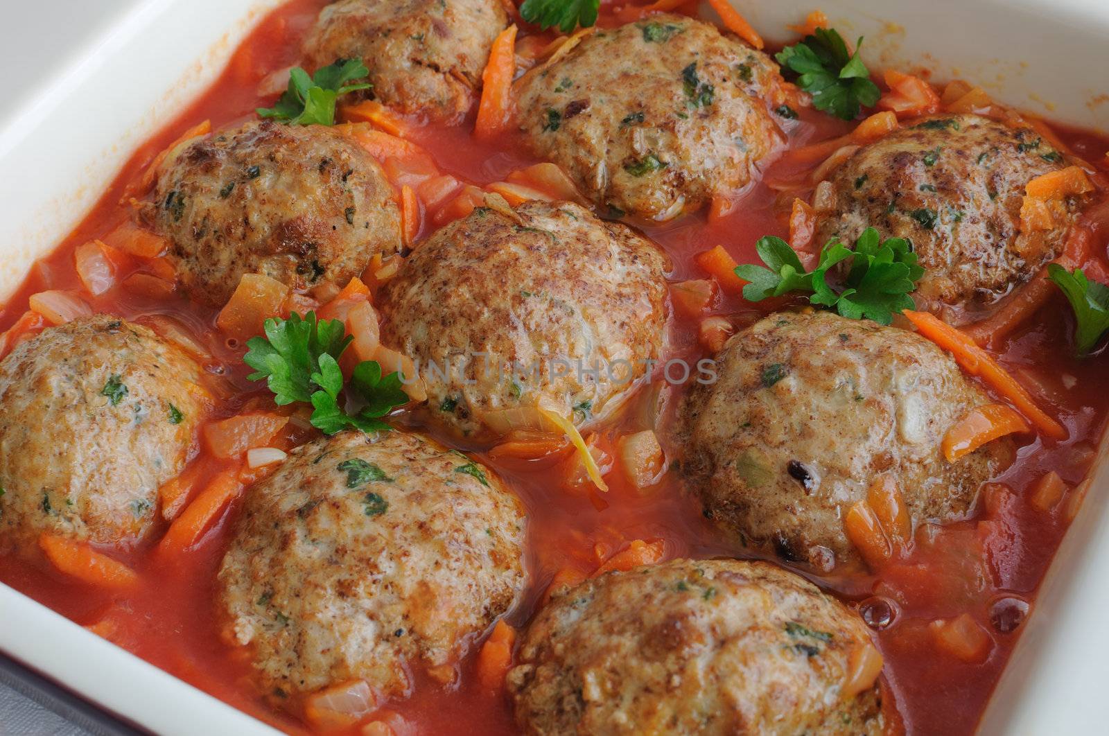 Meatballs with herbs and tomato sauce in a saucepan closeup