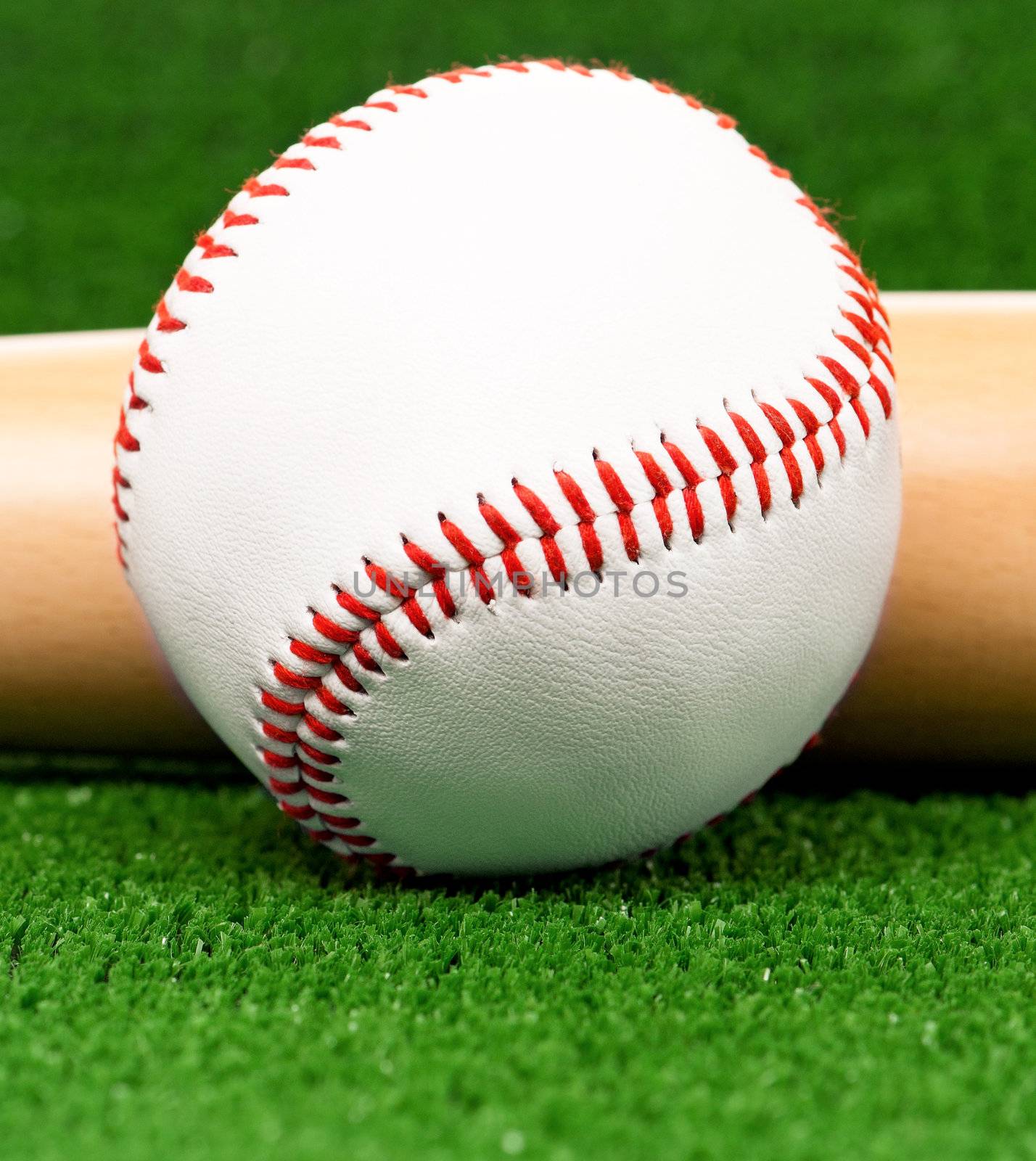 Close-up of baseball ball and bat on artificial green grass