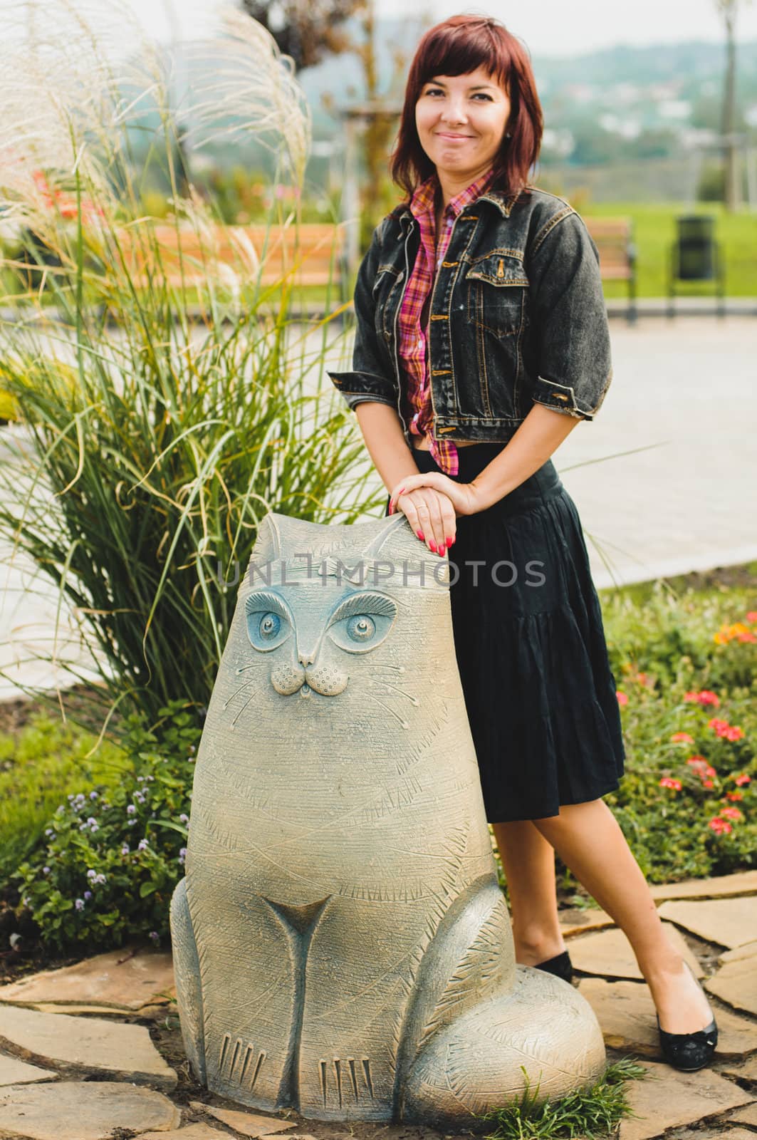 Young woman standing near funny cat statue by nvelichko