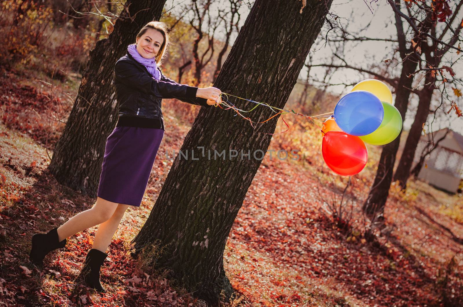 Young pregnant woman with colorful balloons in autumn forest