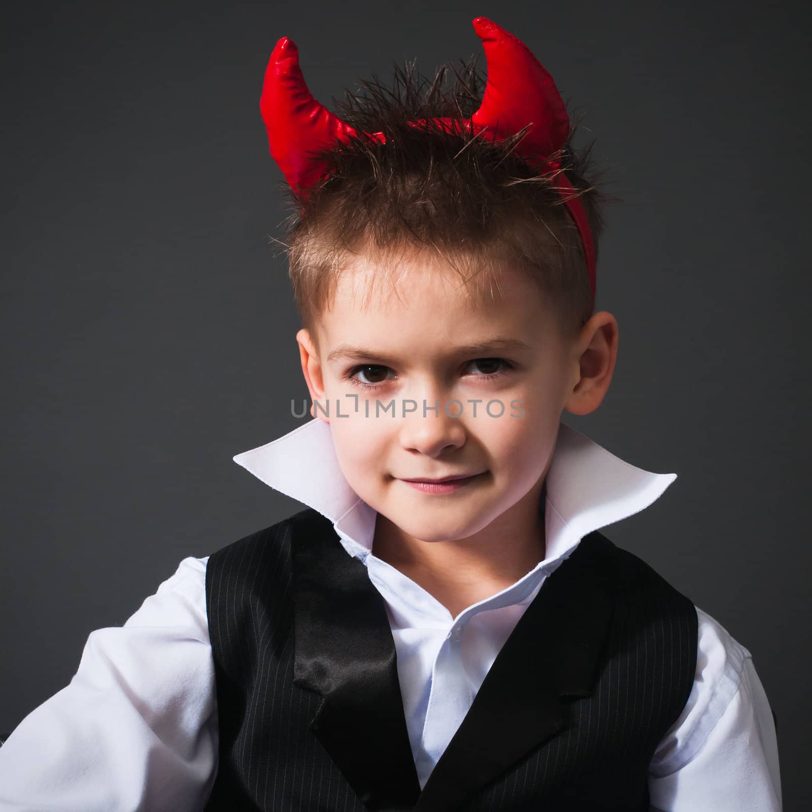 Cool little boy in a waistcoat isolated on gray background