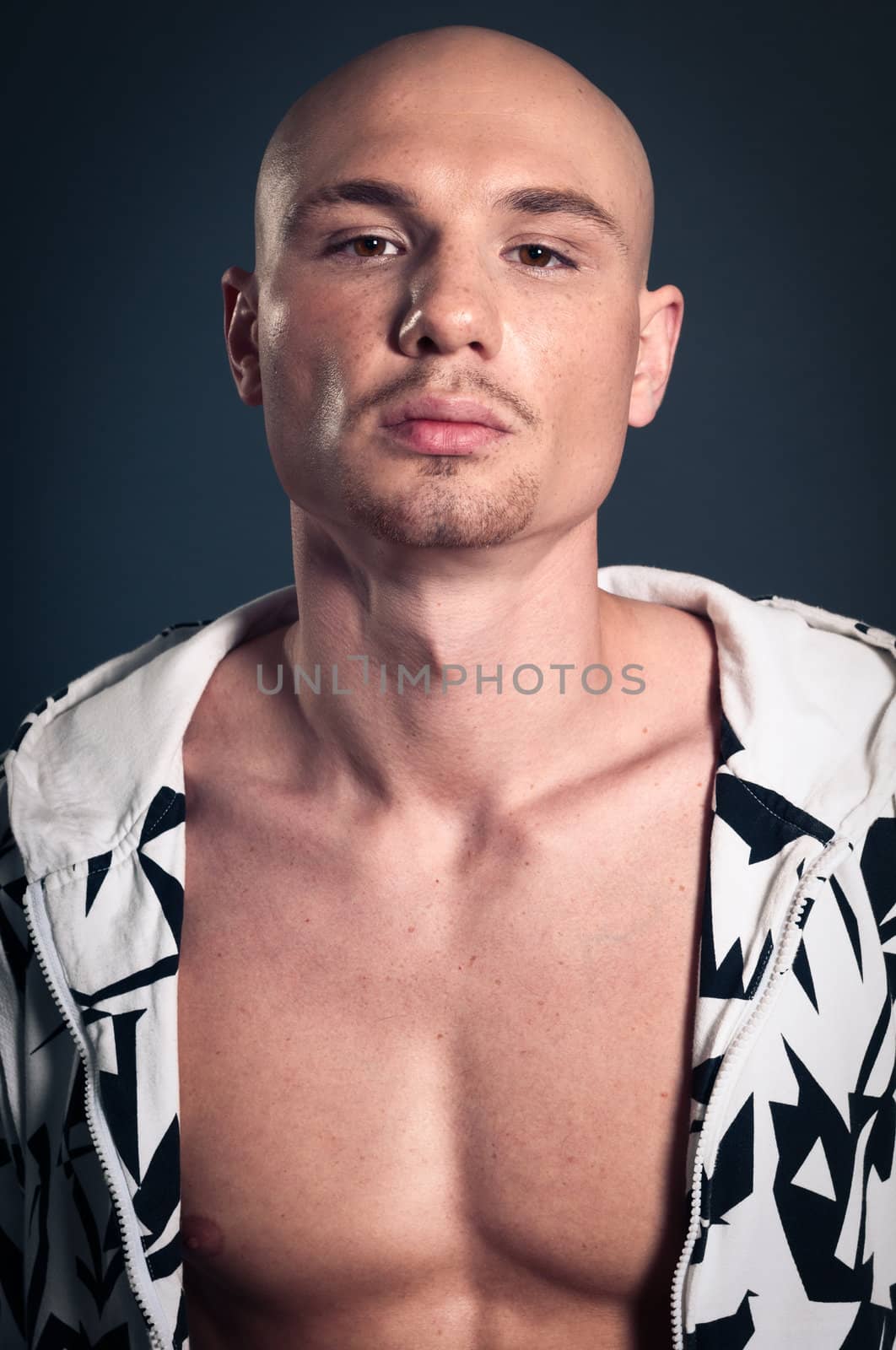 Portrait of naked athletic man posing over gray background