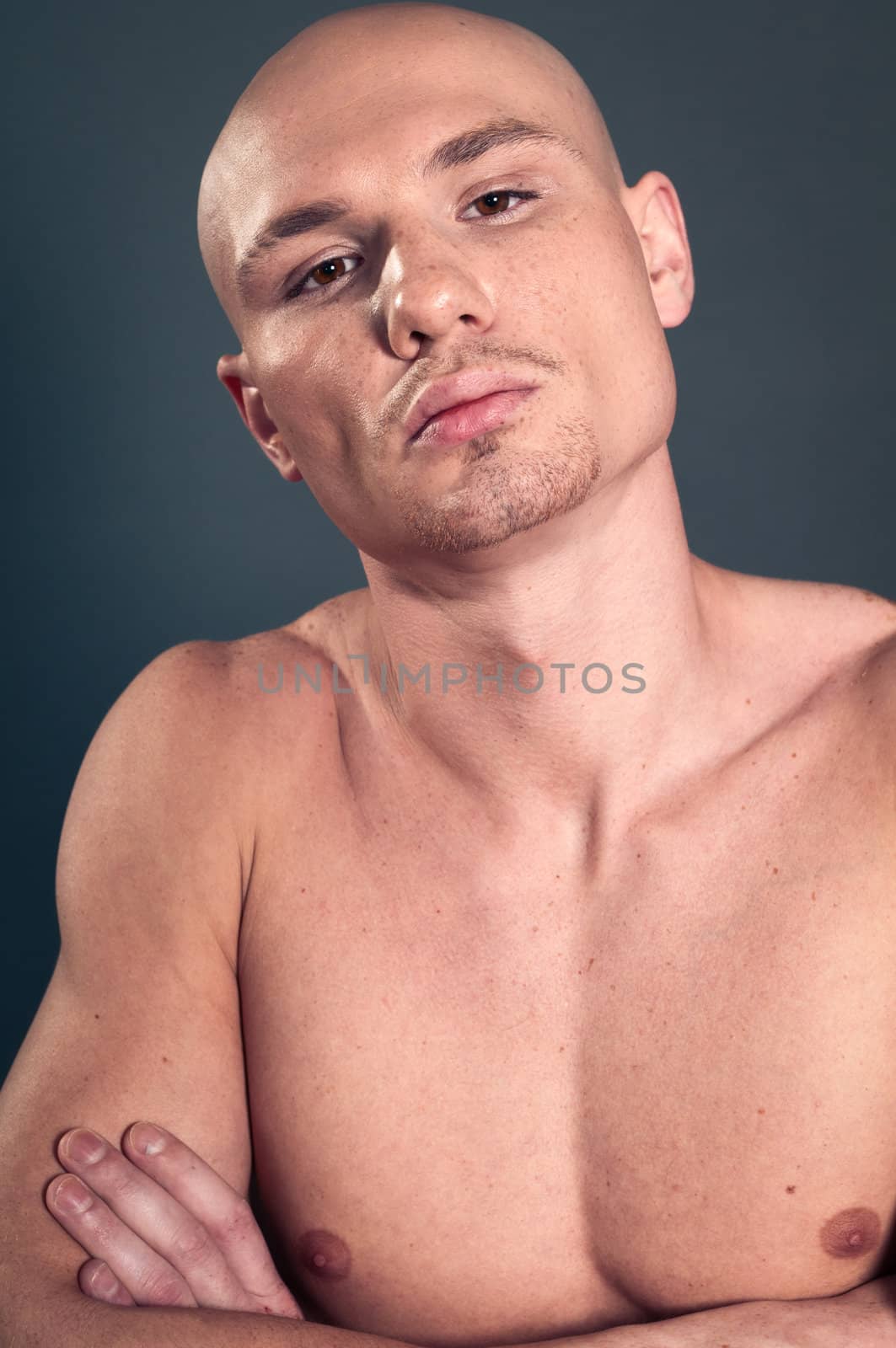 Portrait of naked athletic man posing over gray background