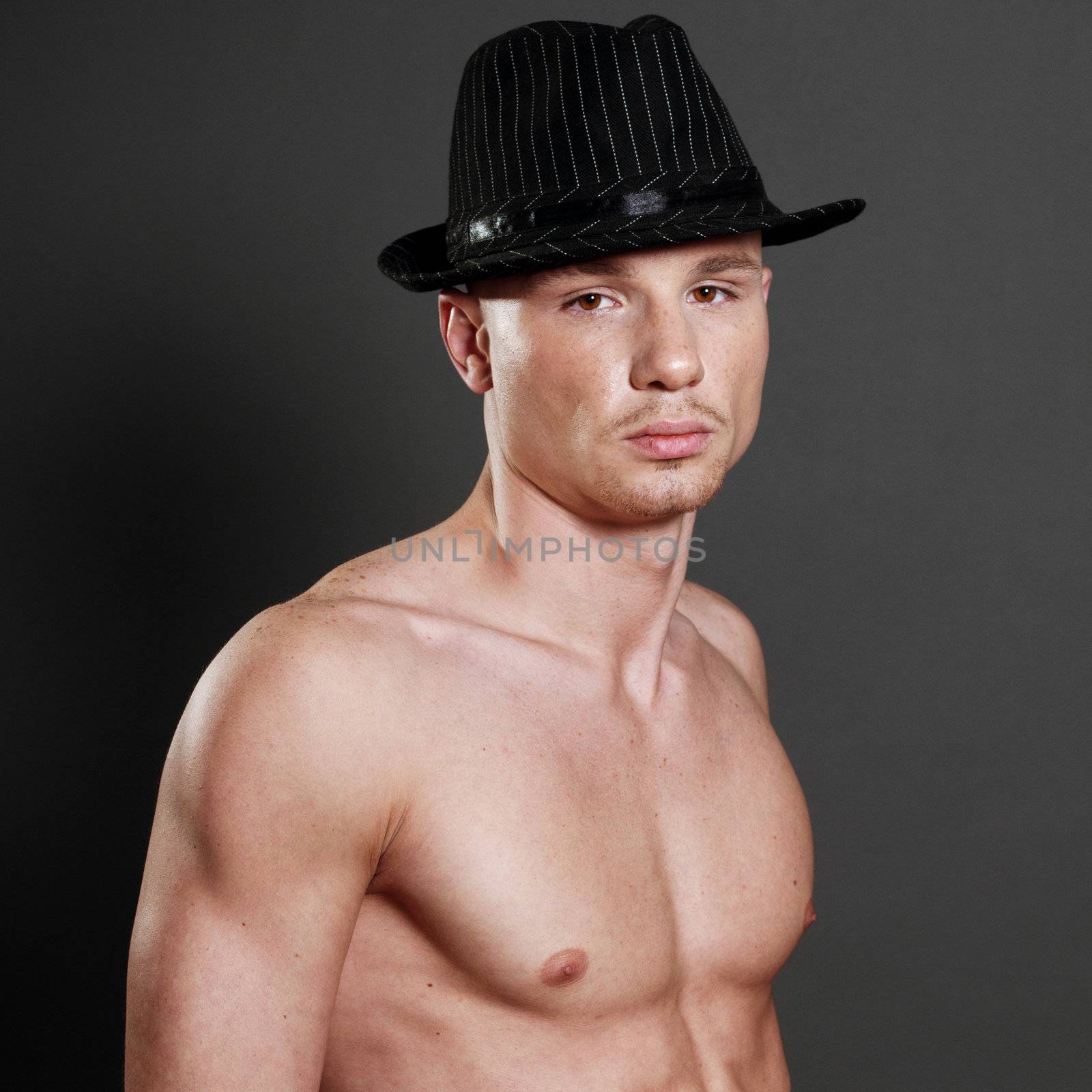 Studio portrait of young bald muscular man with black hat
