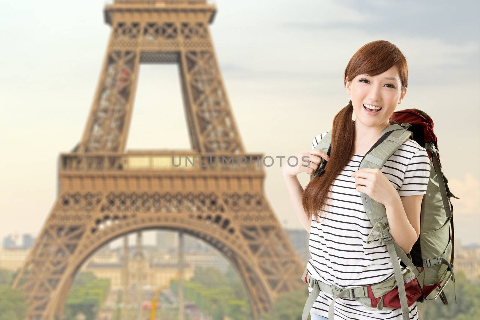 Happy smiling Asian woman travel and look at you in front of famous landmark, Eiffel tower in Paris, France.