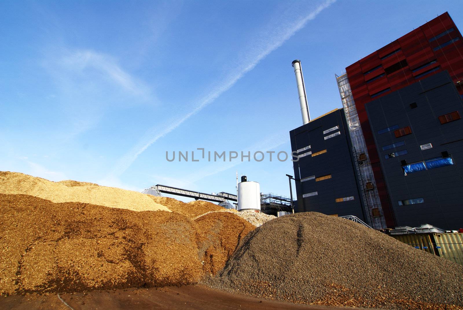 power plant with storage of wooden fuel against blue sky